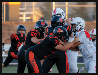 Several people in football uniforms are engaged in a close play on a field during a game. Description generated by AI