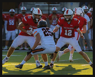 Three people in football uniforms are engaged in a play on a field with two wearing red jerseys labeled “Red Raiders" and one in a white jersey with the number 25. Description generated by AI