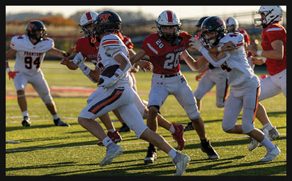 People in football uniforms are actively running and engaging in a game on a sunlit field. Description generated by AI