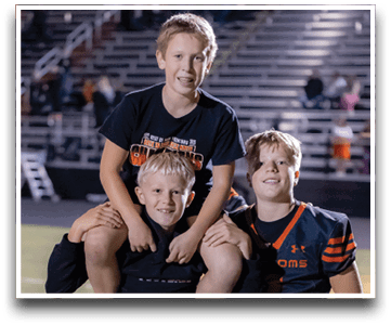 Three football players are standing on the field, one of them is smiling and wearing a black jersey with the number 55. AI generated content