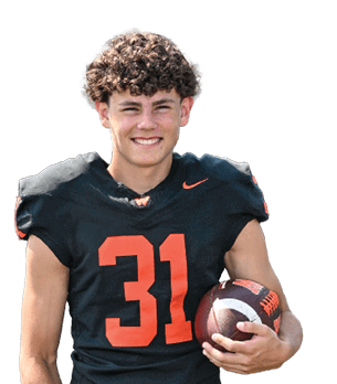 A smiling person with curly hair wearing a dark sports jersey is shown against a white background. Description generated by AI
