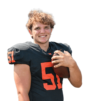 A person with curly hair is smiling and wearing a black football jersey with the number 51 while holding a football. Description generated by AI
