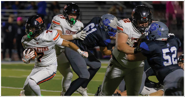 A group of people in football uniforms are actively playing on a field with one person running while holding the ball and others attempting to block or tackle. Description generated by AI