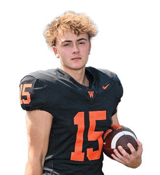 A person with curly hair wearing a black football jersey with the number 15 in orange is holding a football. Description generated by AI