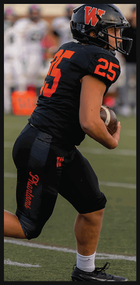 A person wearing a black football uniform with the number 25 is running on a field while holding a football. Description generated by AI