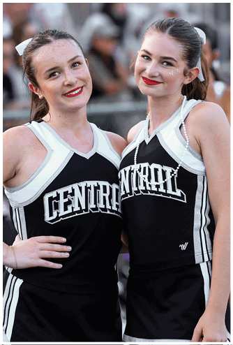 Two adults wearing matching black and white cheerleading uniforms with the word “CENTRAL" smile and pose closely together. Descripci n generada con IA