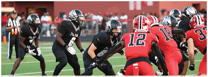 People in football uniforms are positioned on a field preparing for a play during a game. Descripci n generada con IA