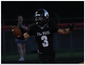 A person wearing a black football uniform with the number 3 is running into the end zone holding a football while another person in a similar uniform runs behind. Descripci n generada con IA