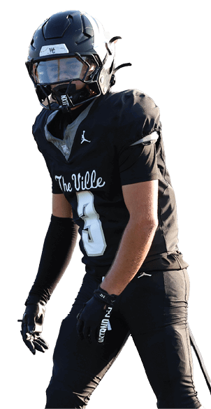 A person wearing a black football uniform and helmet is standing on a football field during a game. Descripci n generada con IA