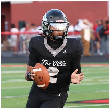 A person wearing a black football uniform and helmet is running on a green football field while holding a football. Descripci n generada con IA