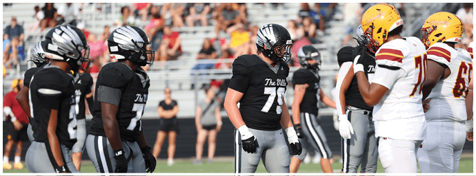 People wearing black and white football uniforms are standing on a field facing each other during a game. Descripci n generada con IA