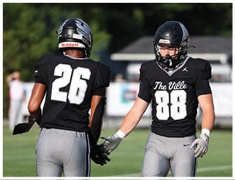 A person wearing a black football uniform with the number 88 and the words “The Ville" on the front is standing outdoors. Descripci n generada con IA