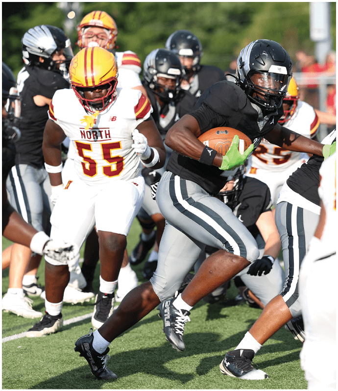 People wearing football uniforms are actively engaged in a play on a grassy field during a game. Descripci n generada con IA