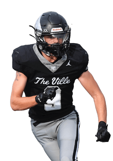 Two people in football uniforms are actively engaged on a football field with one person running and the other preparing to defend. Descripci n generada con IA