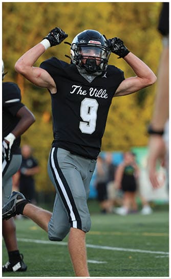 A person wearing a black football uniform with the number nine flexes their arm while standing outdoors with a blurred background. Descripci n generada con IA