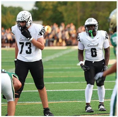 A person wearing a white football jersey with the word Central and the number 6 stands on a field facing another player in a green jersey. Descripci n generada con IA