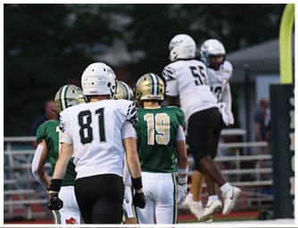 Several people in football uniforms are on a field near a goalpost, with some walking and others jumping. Descripci n generada con IA
