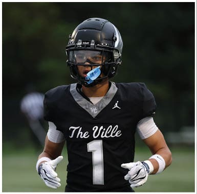 A person wearing a black football helmet and jersey with “The Ville" written on it is looking to the side during a game or practice. Descripci n generada con IA