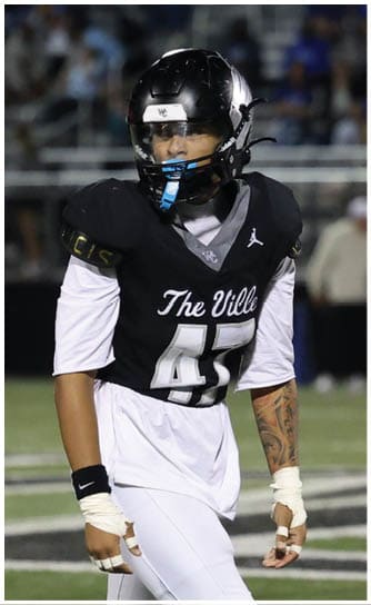 A person wearing a black football jersey with “The Ville" and the number 45 on it is standing on a football field with white athletic tape on their hands and wrists. Descripci n generada con IA
