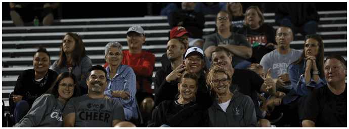 A group of people sitting closely together on bleachers, smiling and appearing to enjoy an event. Descripci n generada con IA