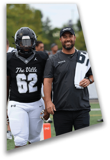 A person wearing a black sports shirt and pants is standing on a field holding a white towel with a number on it over their shoulder. Descripci n generada con IA