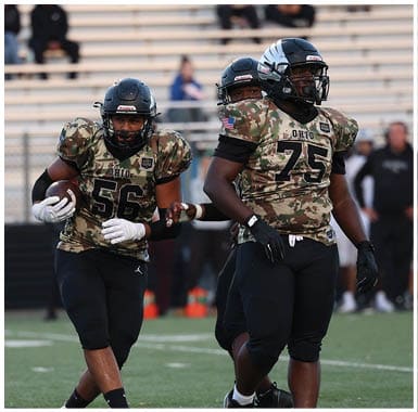 Three people wearing camouflage football uniforms and helmets are on a football field with empty bleachers in the background. Descripci n generada con IA
