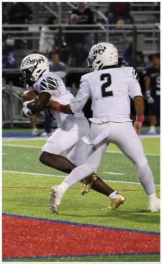 A person in a white football uniform and helmet is running with the ball while another player in white attempts to tackle them on a turf field. Descripci n generada con IA