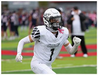 A person in a white football uniform with the number one is running on a green field during a game. Descripci n generada con IA