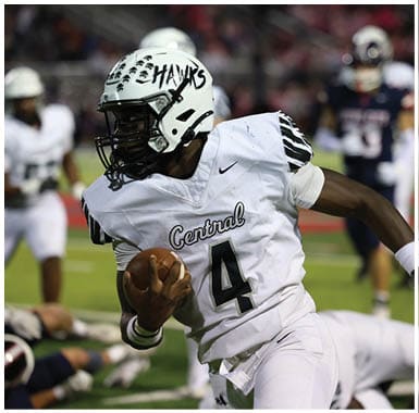A person wearing a white football uniform with “Central" and the number 4 on it is holding a football and appears to be running during a game. Descripci n generada con IA