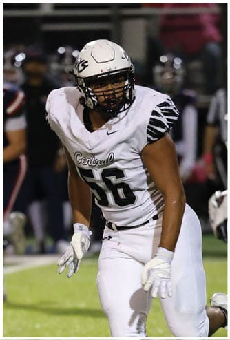 A person wearing a white football uniform with the number 56 and a helmet is on a football field during a game. Descripci n generada con IA