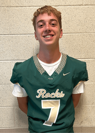 A young man wearing a white and black jersey with the number 14 on it. Description generated by AI