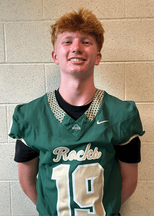 A young man wearing a white and black jersey with the number 14 on it. Description generated by AI
