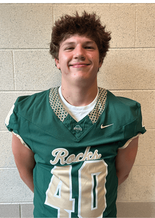 A young man wearing a white and black jersey with the number 14 on it. Description generated by AI