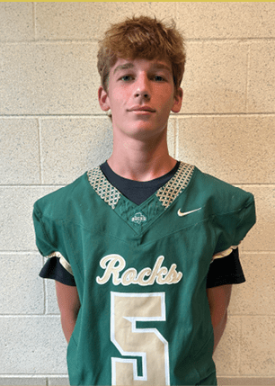 A young man wearing a white and black jersey with the number 14 on it. Description generated by AI