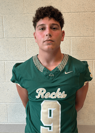 A young man wearing a white and black jersey with the number 14 on it. Description generated by AI