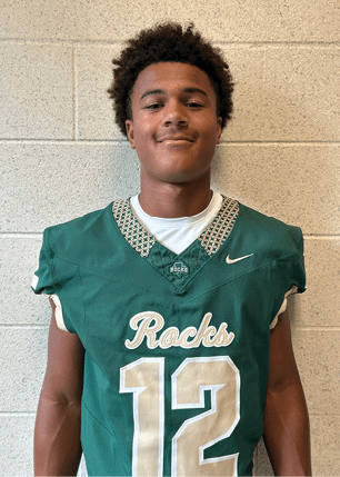 A young man wearing a white and black jersey with the number 14 on it. Description generated by AI