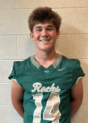 A young man wearing a white and black jersey with the number 14 on it. Description generated by AI