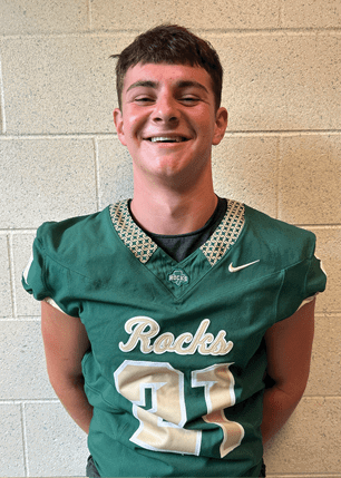 A young man wearing a white and black jersey with the number 14 on it. Description generated by AI