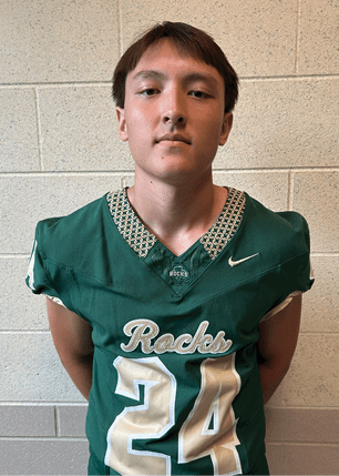 A young man wearing a white and black jersey with the number 14 on it. Description generated by AI