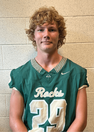 A young man wearing a white and black jersey with the number 14 on it. Description generated by AI