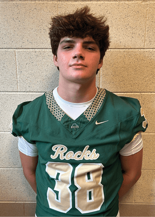 A young man wearing a white and black jersey with the number 14 on it. Description generated by AI
