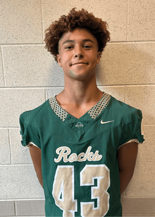 A young man wearing a white and black jersey with the number 14 on it. Description generated by AI