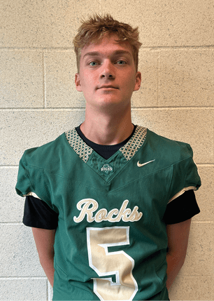 A young man wearing a white and black jersey with the number 14 on it. Description generated by AI