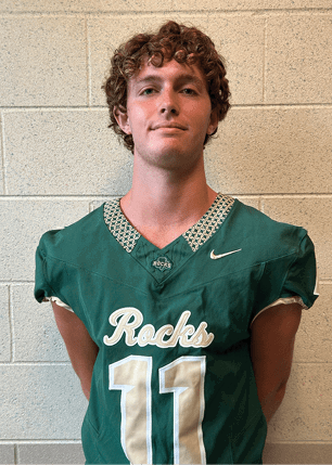 A young man wearing a white and black jersey with the number 14 on it. Description generated by AI