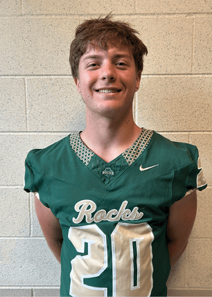 A young man wearing a white and black jersey with the number 14 on it. Description generated by AI