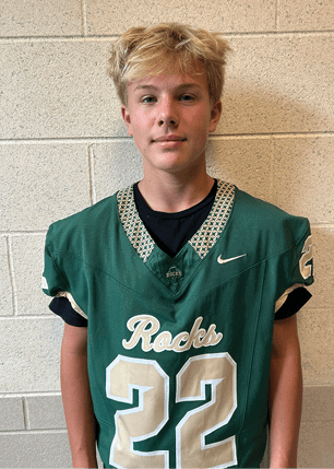 A young man wearing a white and black jersey with the number 14 on it. Description generated by AI