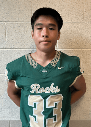 A young man wearing a white and black jersey with the number 14 on it. Description generated by AI