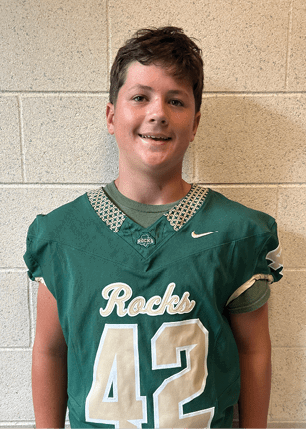 A young man wearing a white and black jersey with the number 14 on it. Description generated by AI