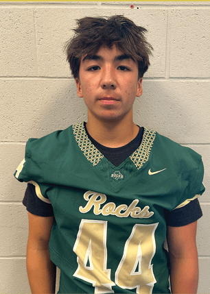 A young man wearing a white and black jersey with the number 14 on it. Description generated by AI
