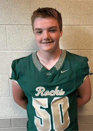 A young man wearing a white and black jersey with the number 14 on it. Description generated by AI